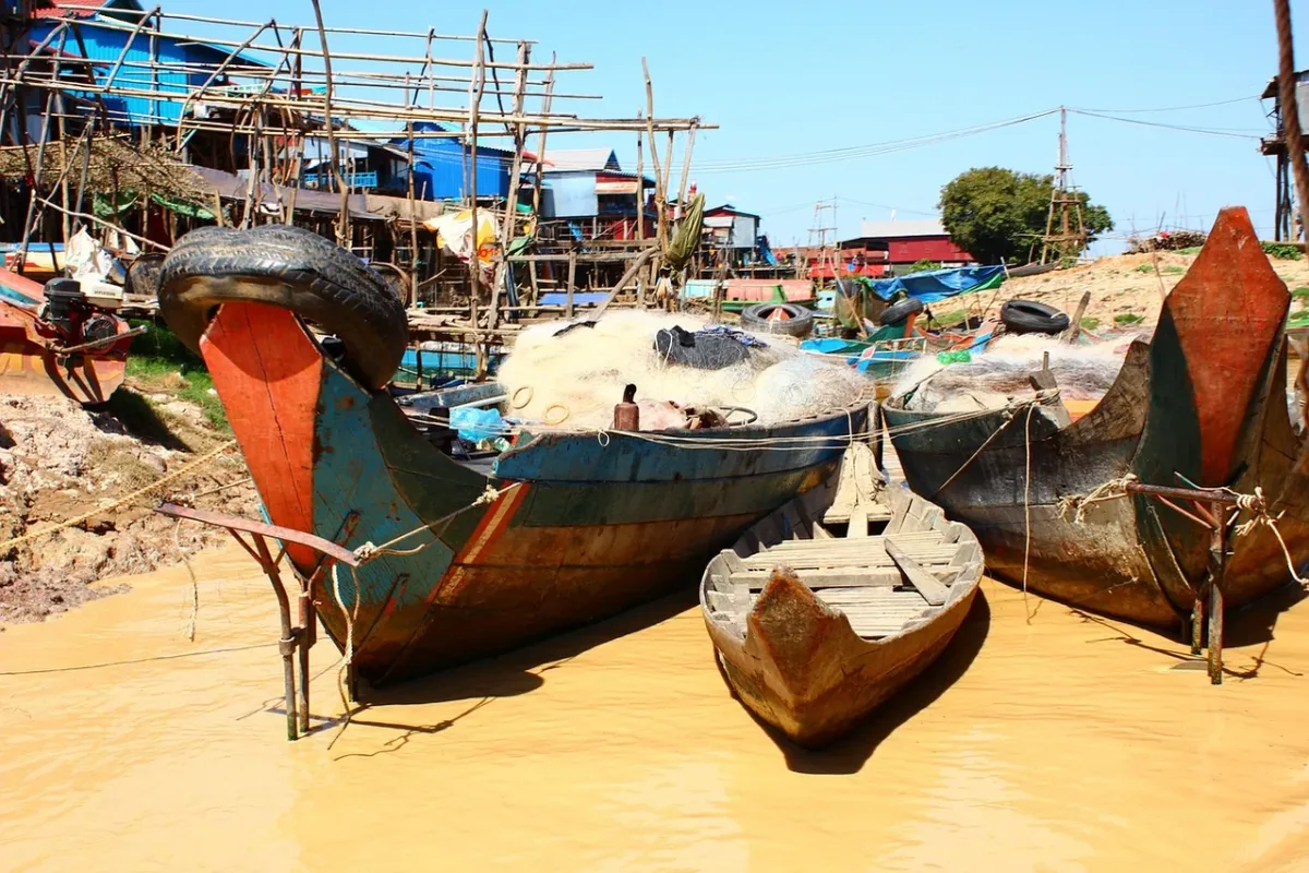 Wooden fishing boats resting on a sandy shore in Cambodia.