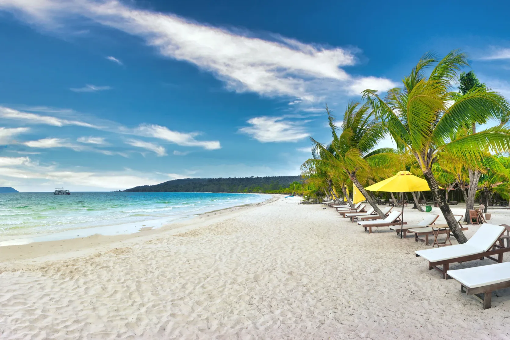 Lounge chairs and palms beside Koh Rong's white sand.