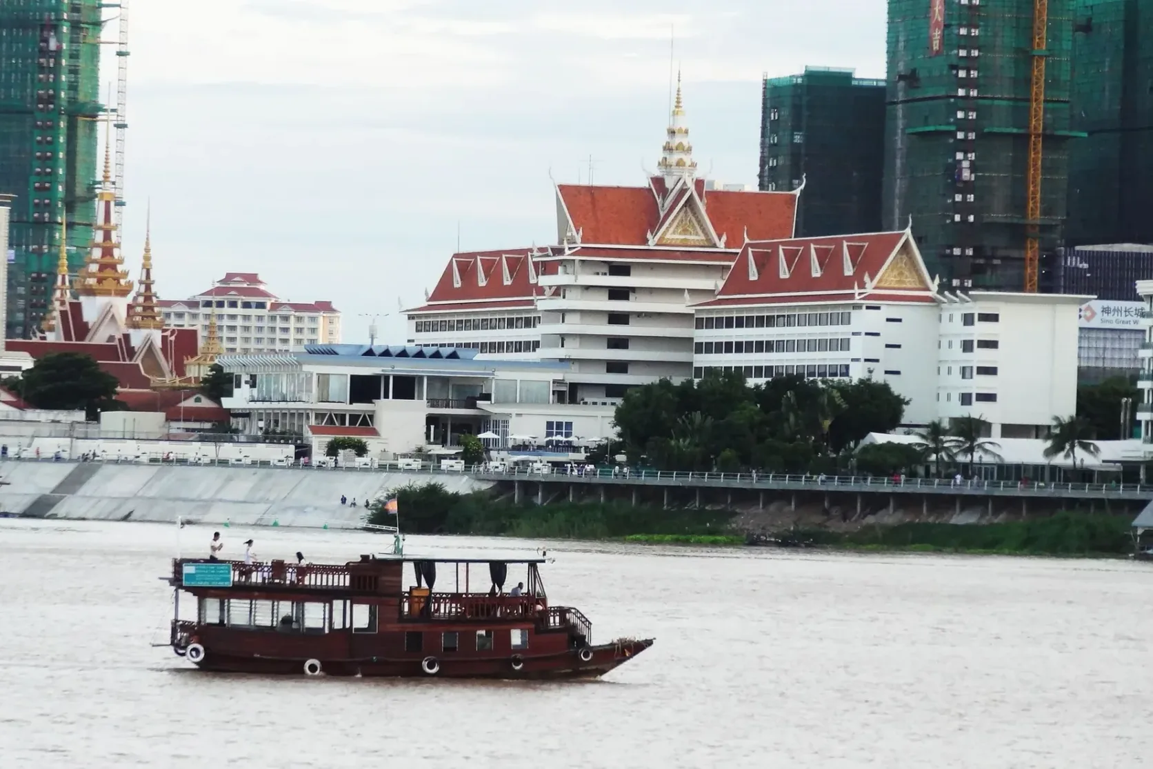 A passenger boat passing buildings on Phnom Penh's riverfront.