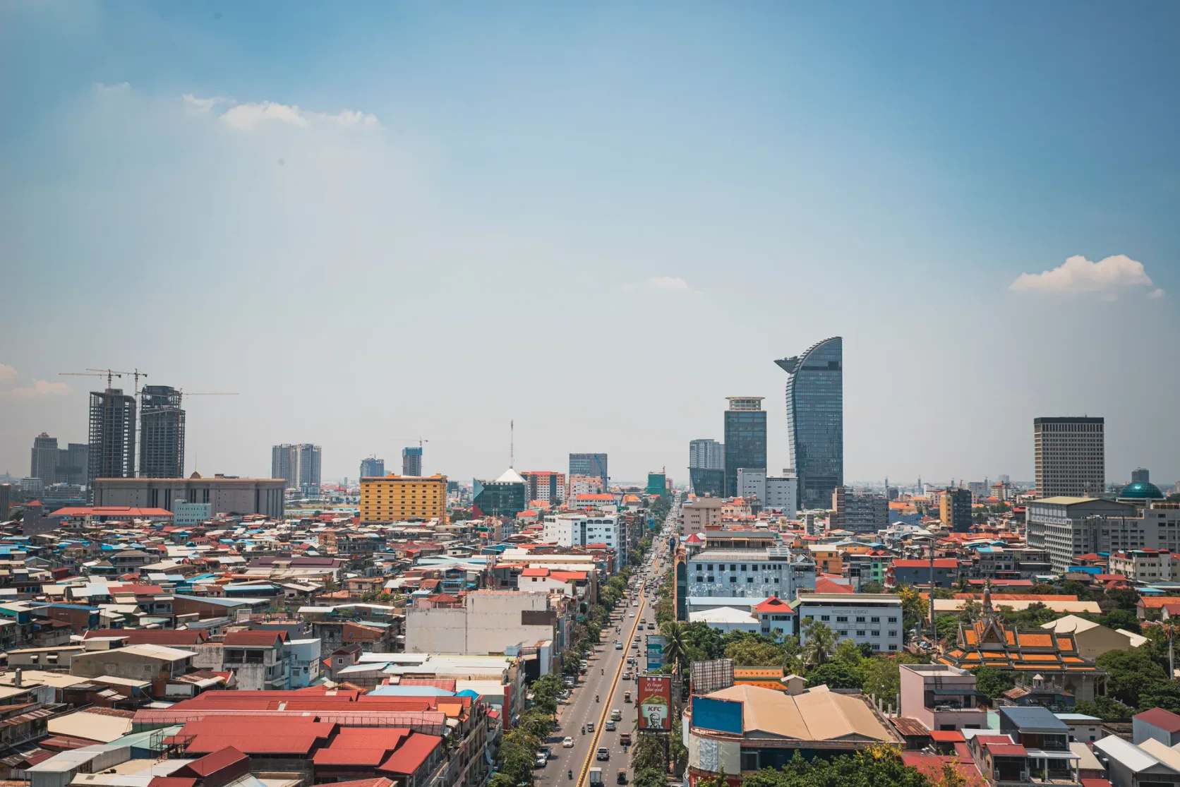 Phnom Penh's rooftops and modern towers under a blue sky.