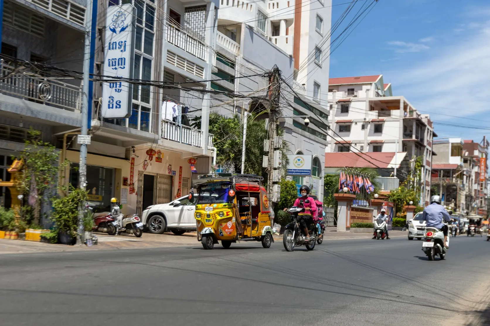 Tuk-tuks and motorbikes on a street in Phnom Penh.